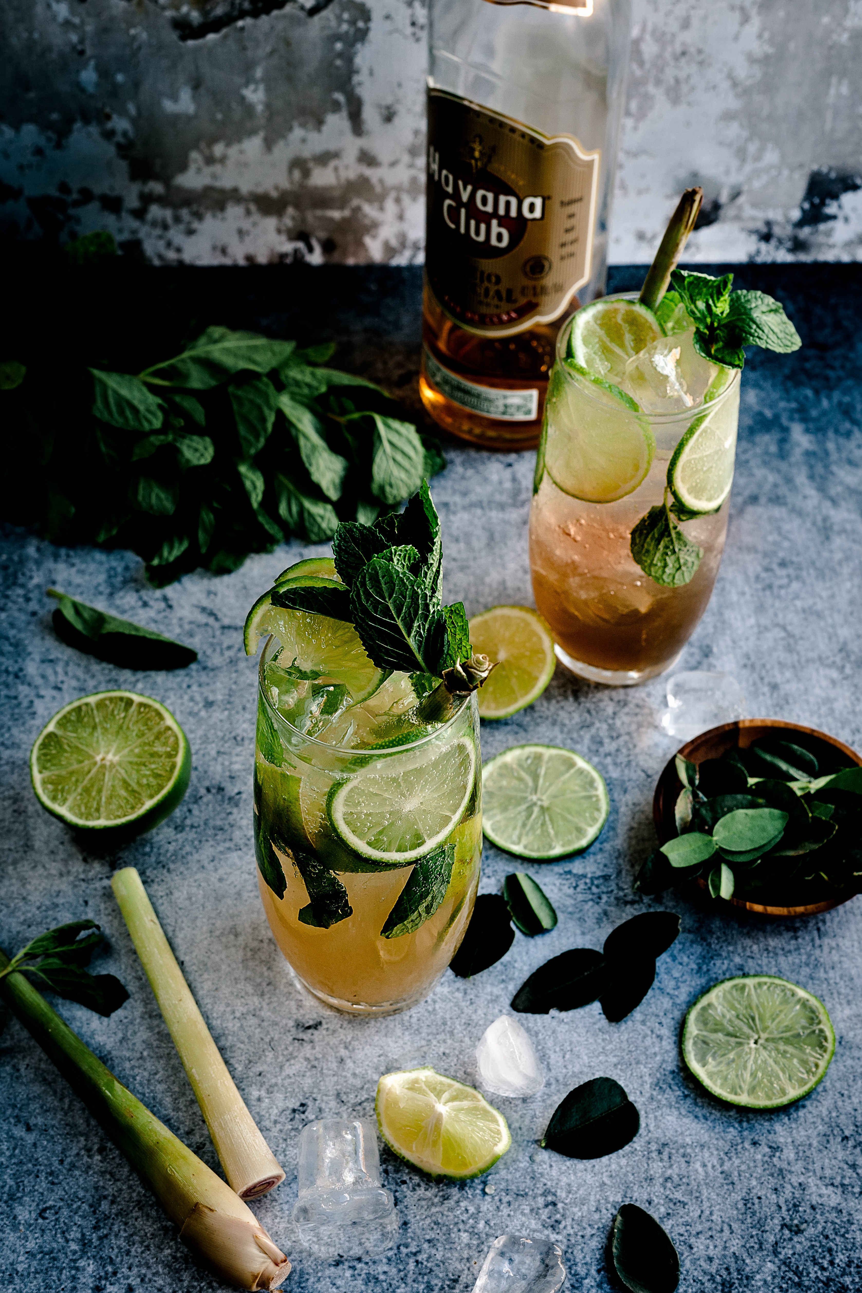 Two glasses filled with rum cocktail,
              garnished with mint and fresh lime.